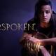 Forspoken's Frey Holland stands in front of a smokey purple background with her hand over her magical glowing cuffs.